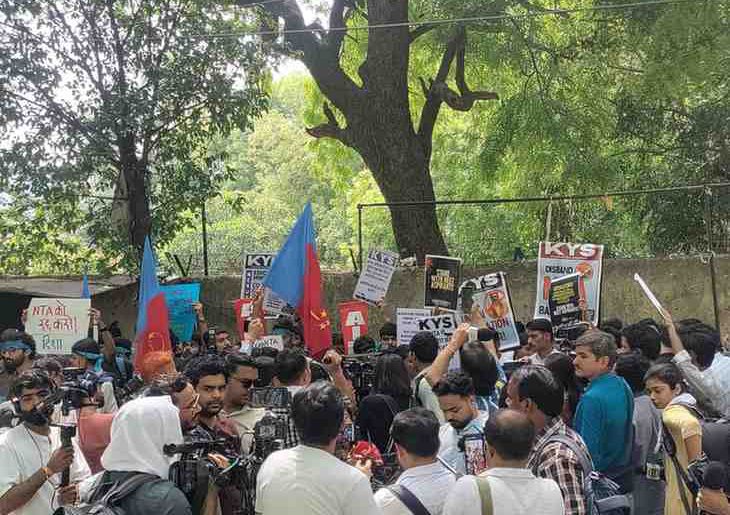 Students and activists protest at Jantar Mantar with banners and flags against the NEET 2026 paper leak and re-exam announcement.