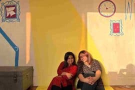 Sneha and Navya Misran at the library in Tughlakabad Village, against a wall painted by Kitaab Club and the children.