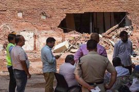 People gather outside a partially collapsed building at a Satya Niketan collapse site.