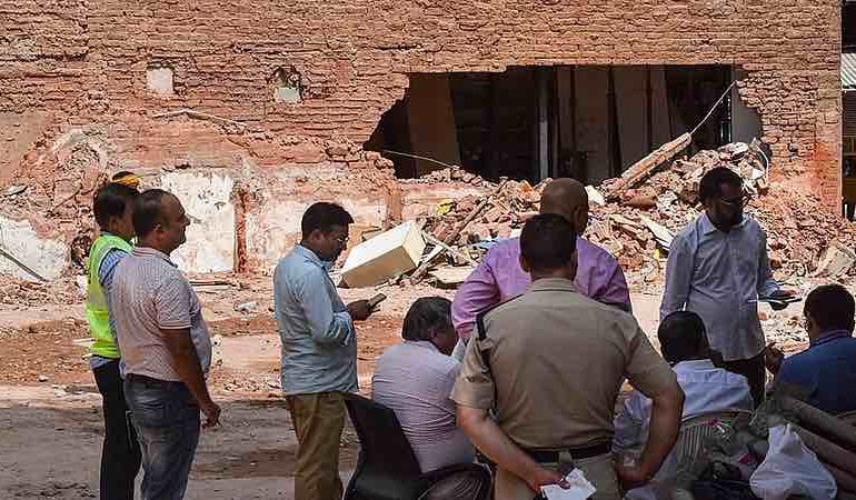 People gather outside a partially collapsed building at a Satya Niketan collapse site.
